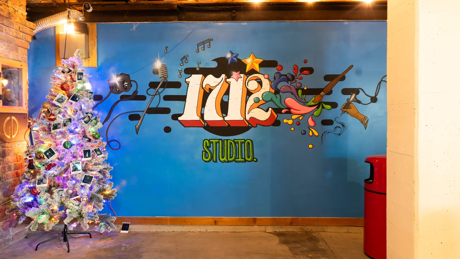 The blue 1712 Studio mural with a lit holiday tree in the Back Venue at 1712 Studios