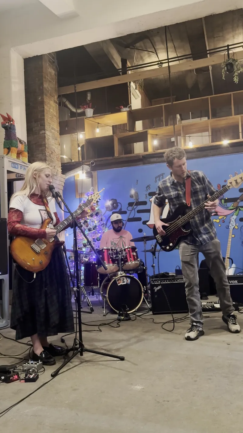 A singer with a guitar and a drummer on the Back Venue stage at 1712 Studios