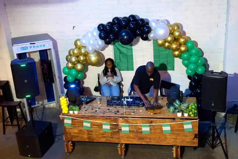 A DJ playing under a black, gold and green balloon arch in the Back Venue at 1712 Studios