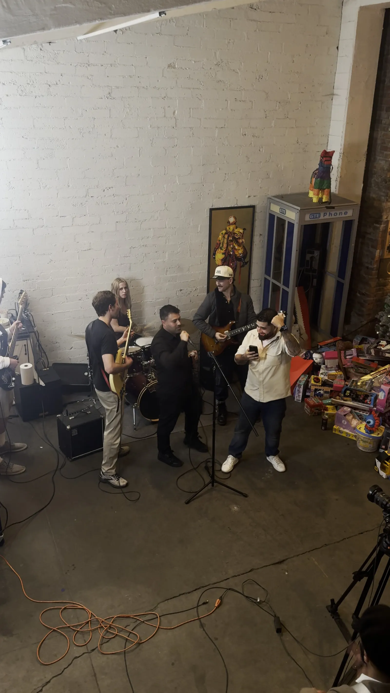 A four piece band playing in front of the white brick in the Back Venue at 1712 Studios at a December party
