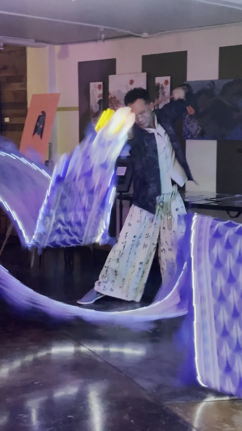 A performer with glowing light wings in the Back Venue at 1712 Studios