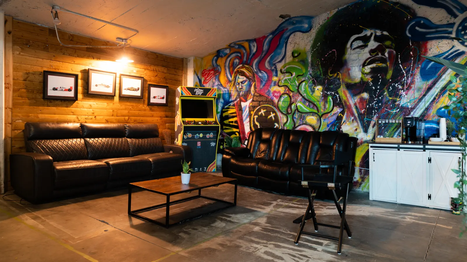 The Back Venue lounge at 1712 Studios with leather couches, an arcade cabinet and a painted mural wall