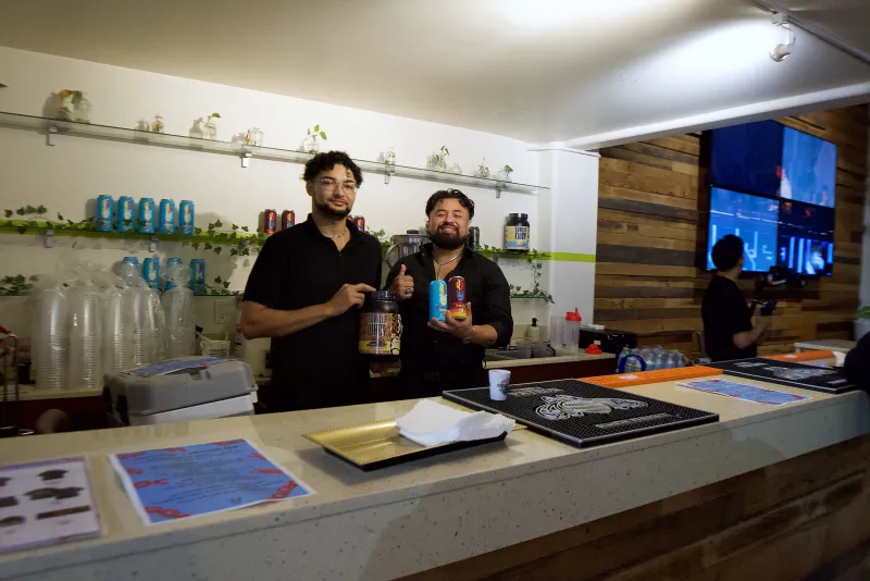 Two bartenders behind the downstairs bar in the Main Hall at 1712 Studios with the shelves lit