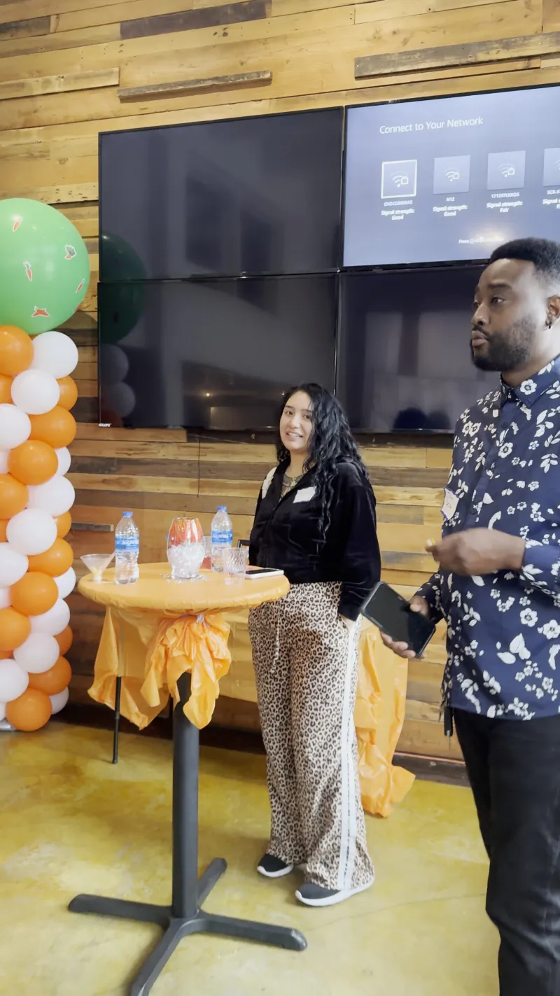 A speaker at a cocktail table with a balloon arch in the Main Hall at 1712 Studios
