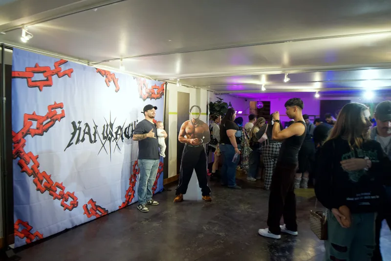 Guests in front of a branded backdrop under purple light in the Main Hall at 1712 Studios