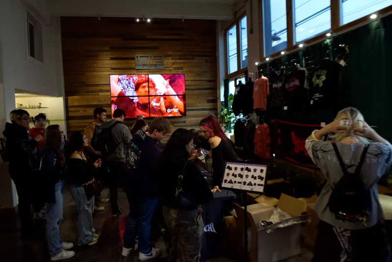 A crowd browsing merch tables under the screen in the Main Hall at 1712 Studios on a pop up night
