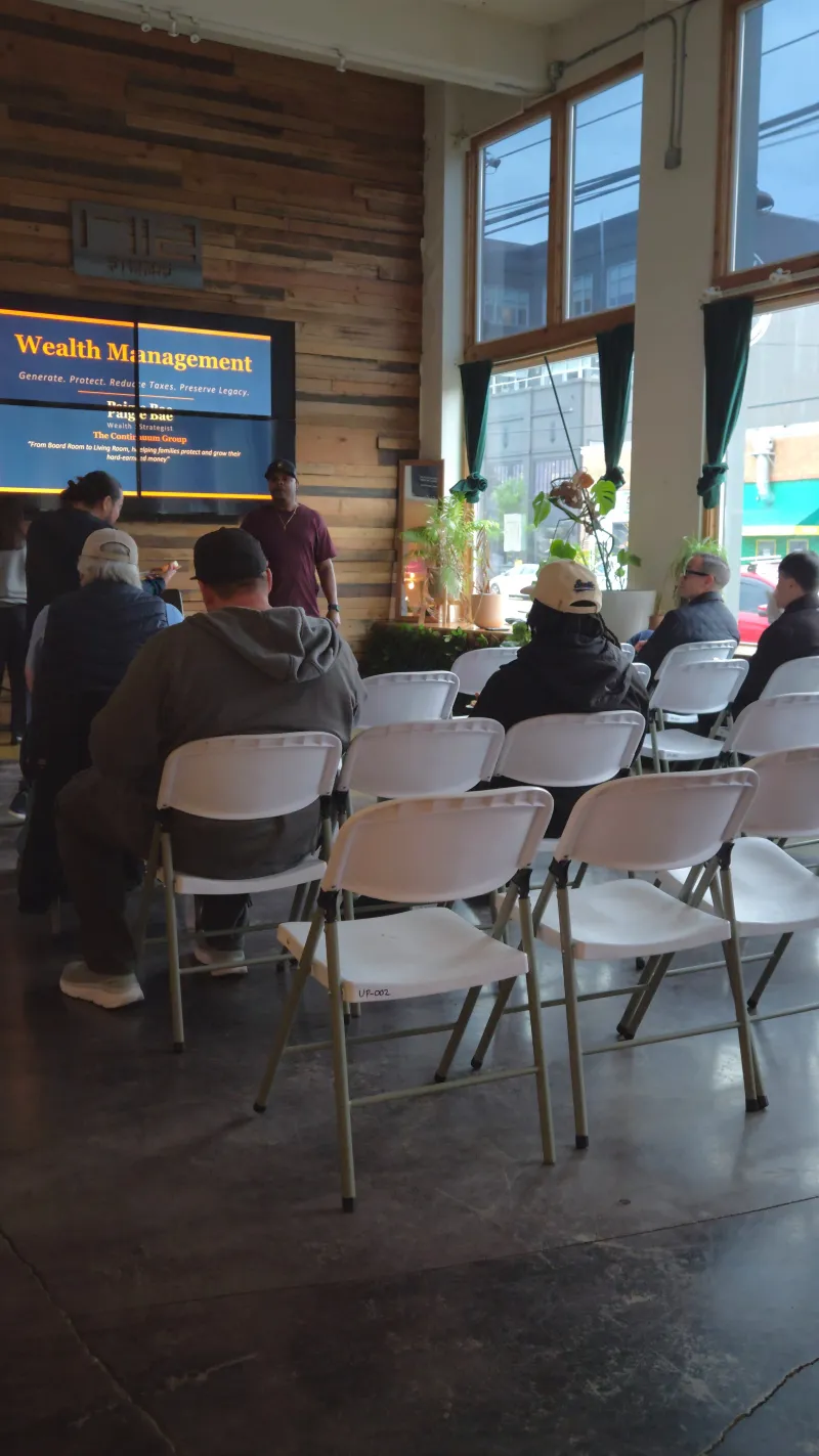 Attendees in rows of chairs watching a speaker on the 110 inch screen in the Main Hall at 1712 Studios