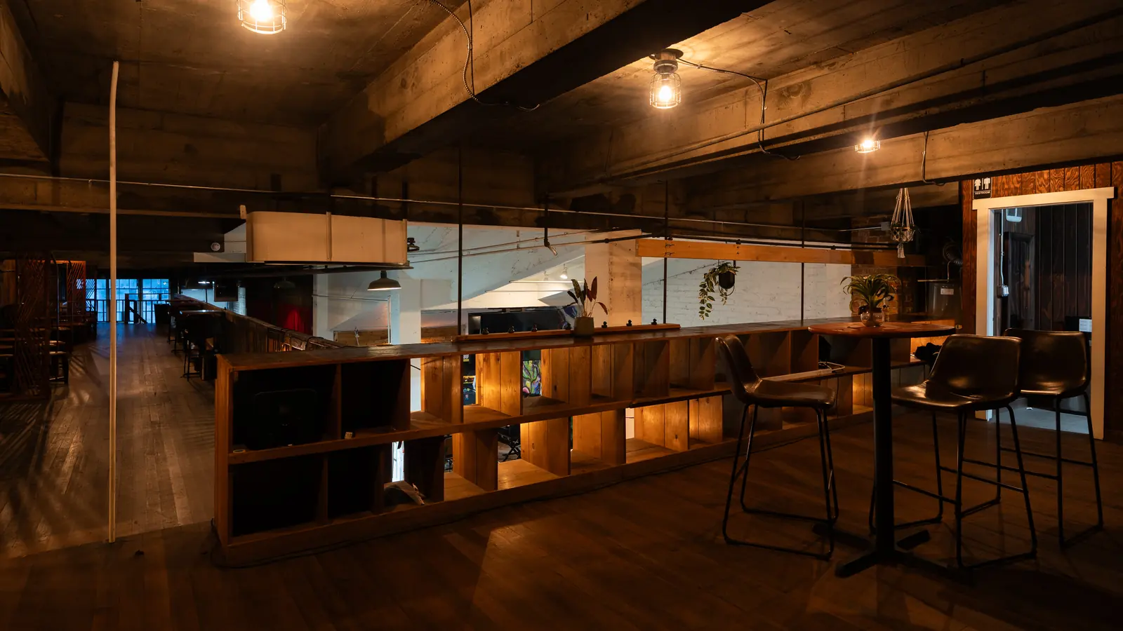 Bar stools and lit wood shelving in the Speakeasy upstairs at 1712 Studios, dark wood and Edison bulbs