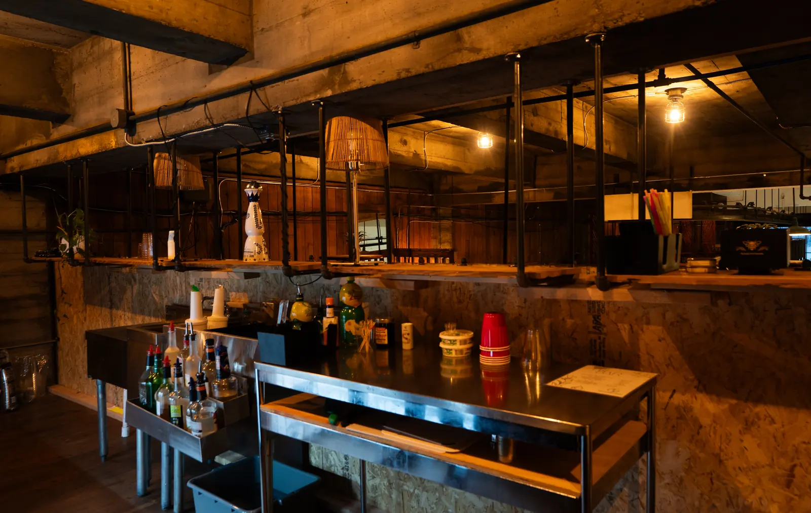 The Speakeasy bar station at 1712 Studios with bottles, ice wells and copper pendant lights